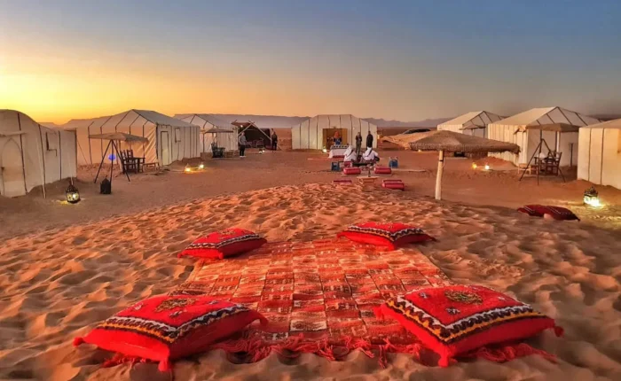 A serene desert scene featuring tents and colorful pillows arranged on the warm sand on our 2-Day Desert Tour from Marrakech to Zagora