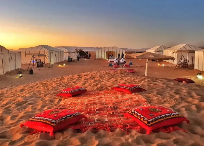 A serene desert scene featuring tents and colorful pillows arranged on the warm sand on our 2-Day Desert Tour from Marrakech to Zagora