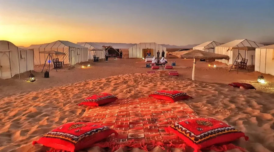 A serene desert scene featuring tents and colorful pillows arranged on the warm sand on our 2-Day Desert Tour from Marrakech to Zagora