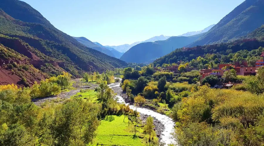 A serene river flows through a lush valley, framed by majestic mountains in the background.